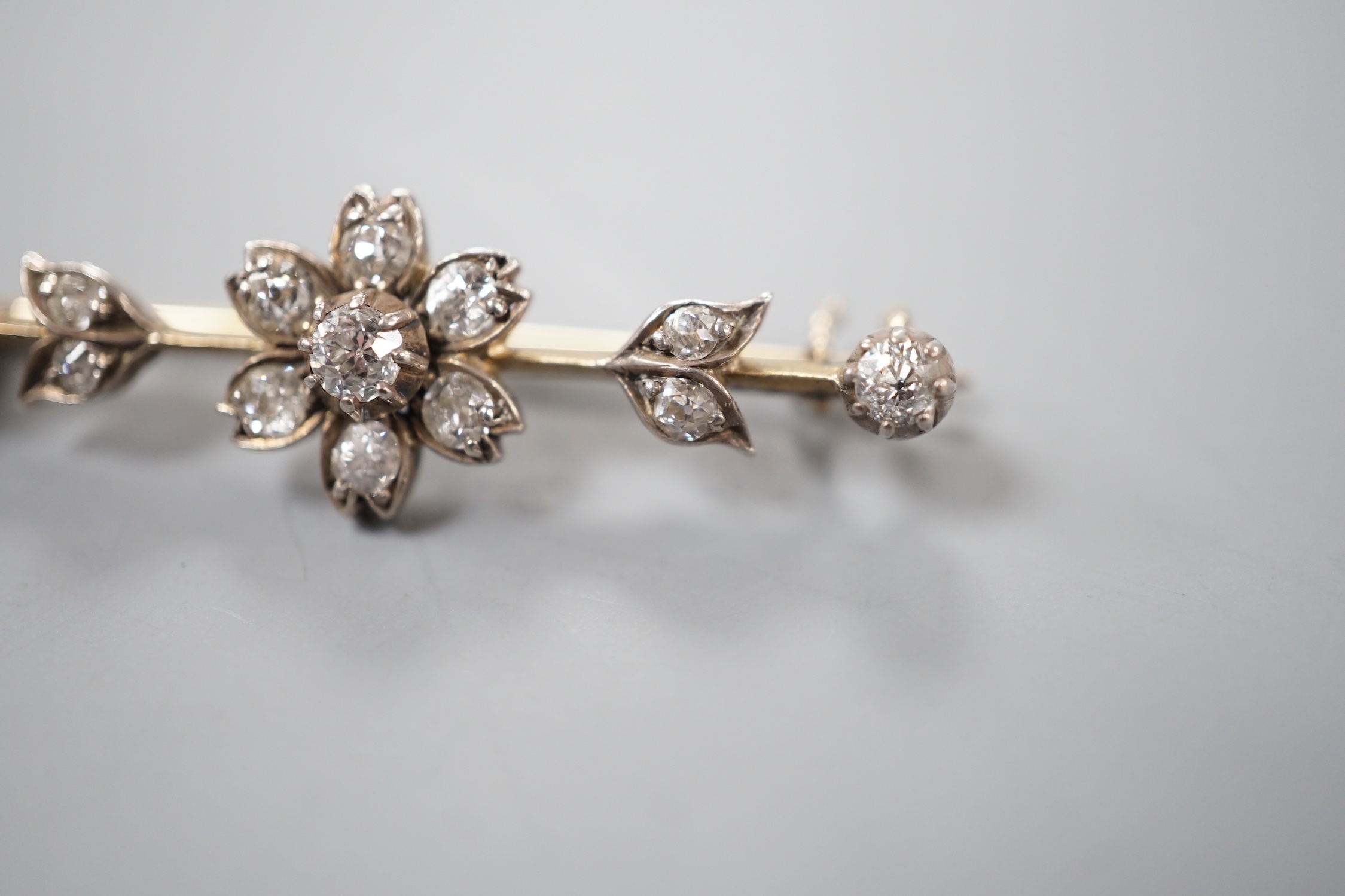 A Victorian yellow metal and diamond flowerhead cluster set bar brooch, 40mm, gross 3.8 grams.